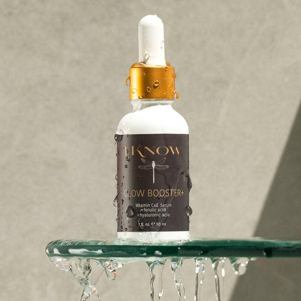 Black woman holding Glow Booster+ Vitamin C & E Serum with radiant, melanin-rich skin